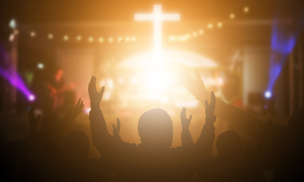 Person raising hands in worship before a cross