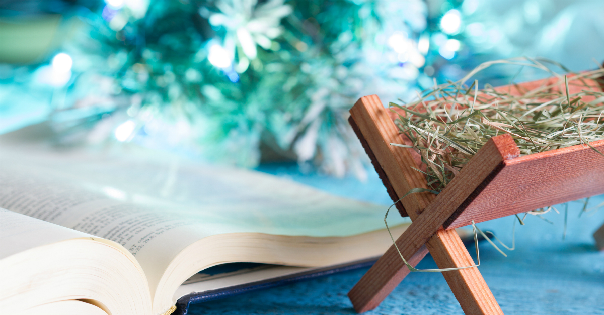 Small wooden manger next to an open Bible