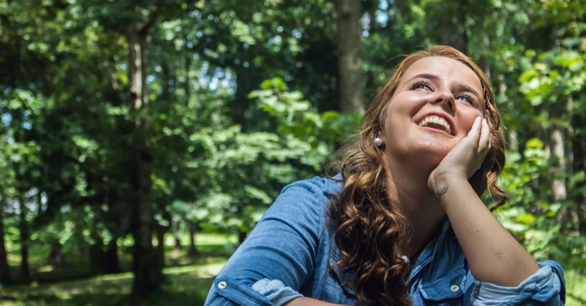 Young woman looking up at the sky happily