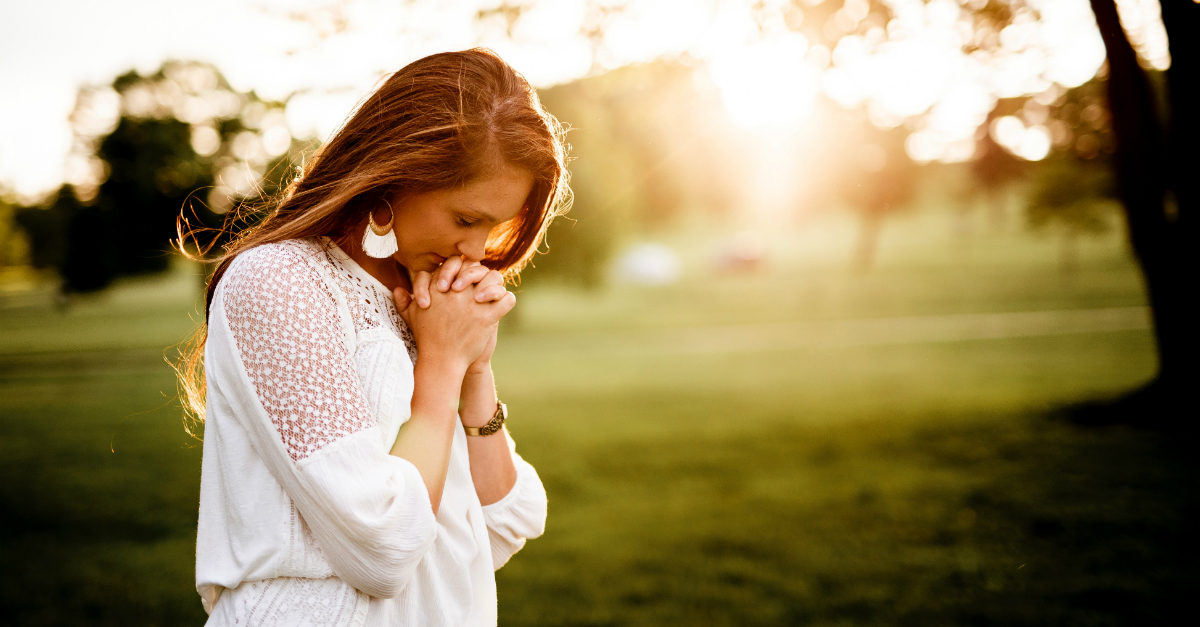 Young woman praying outside
