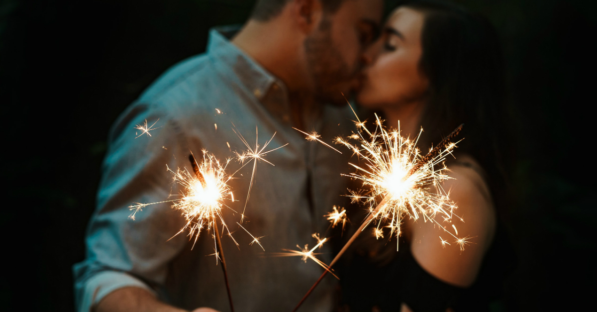 Couple kissing while holding sparklers