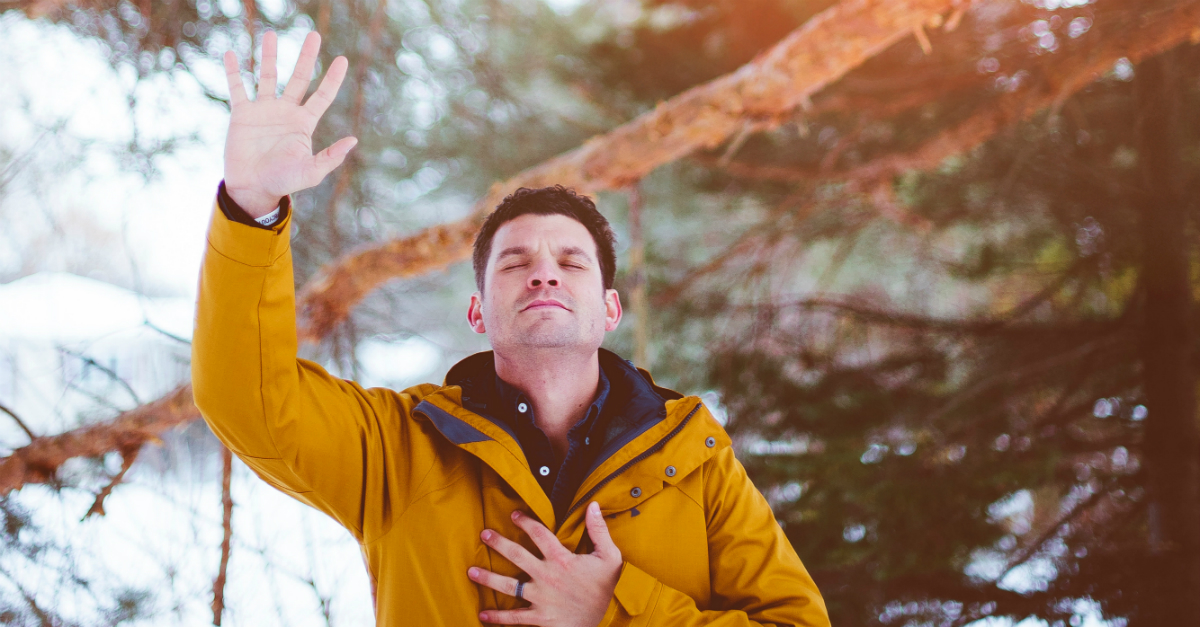 man holding hand up in praise because God answers prayer