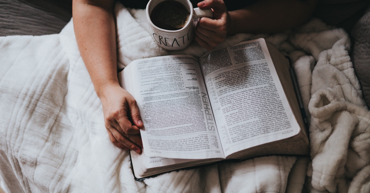 Man reading the Bible in bed with coffee
