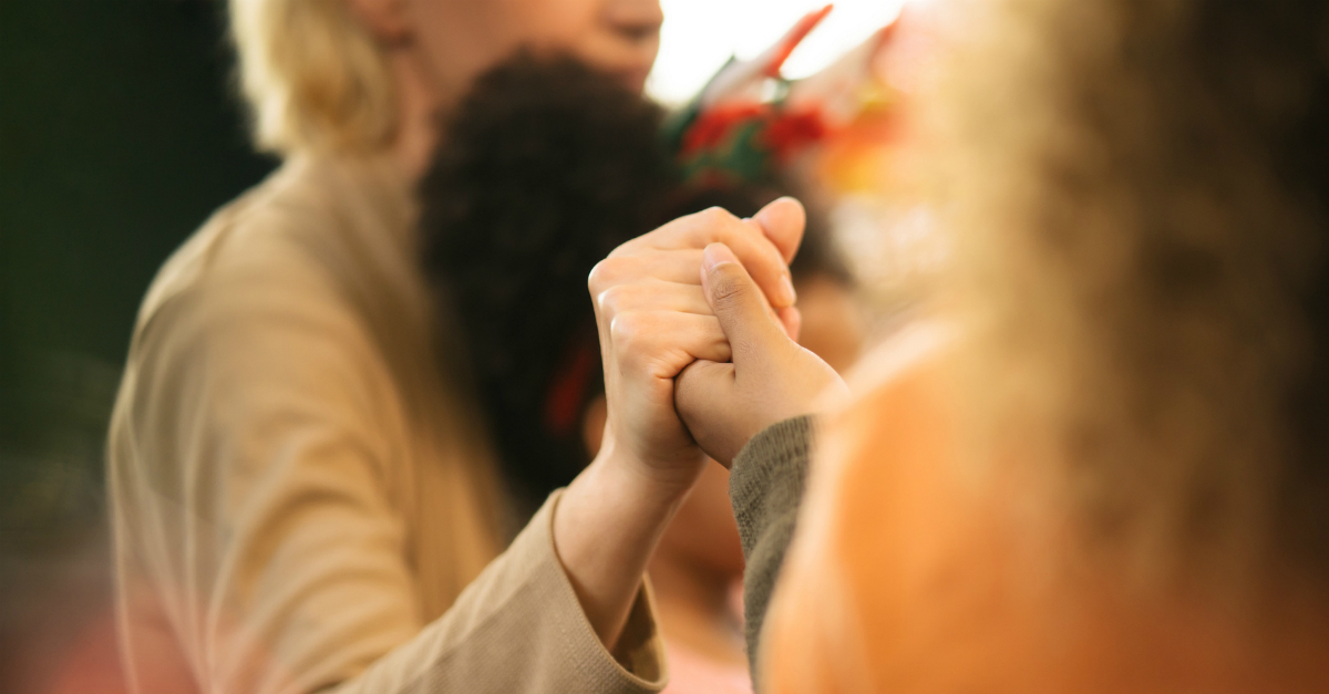 closeup of hands held in group prayer