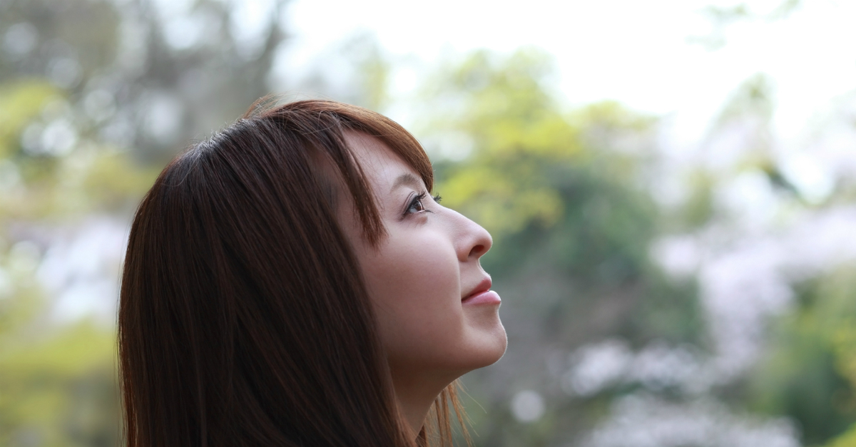 Young woman looking up at the sky, content