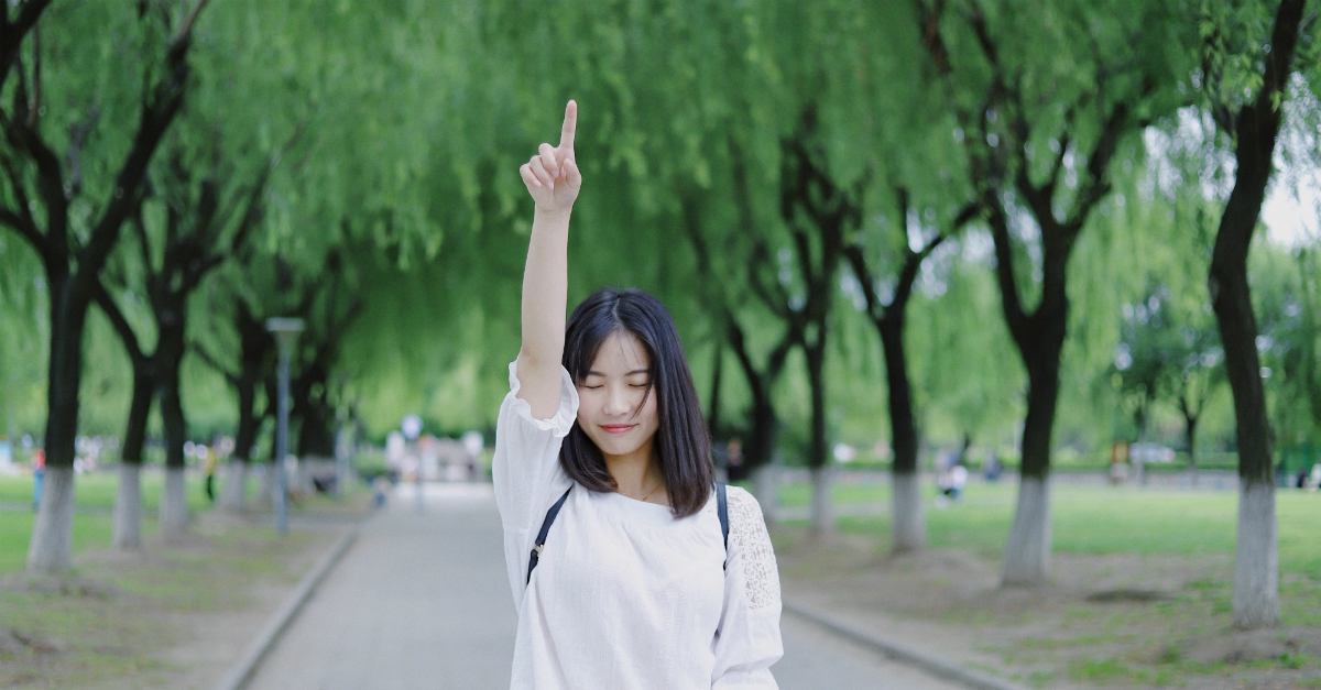 woman pointing up toward the sky as if pointing to Jesus