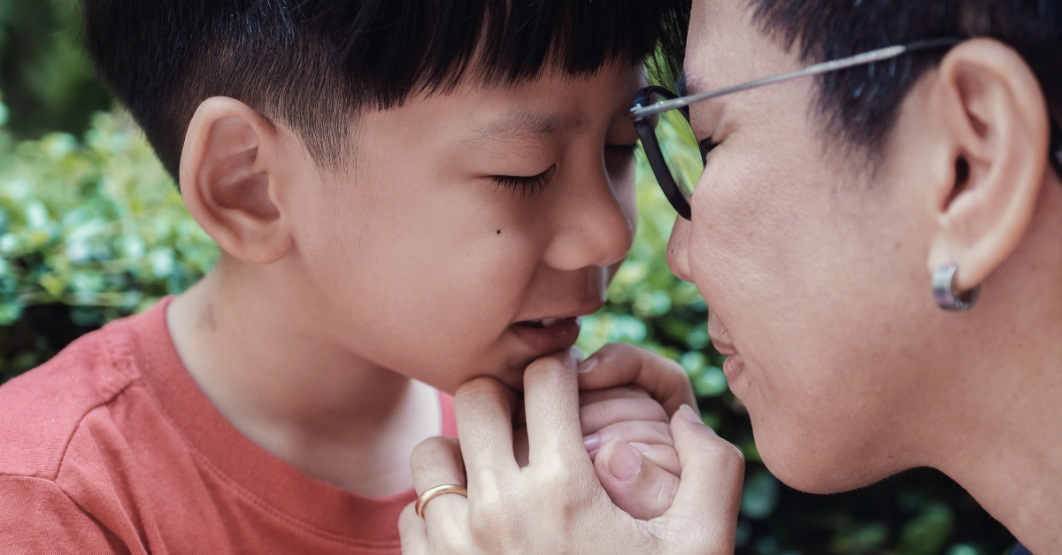 Mom and young son praying with their heads together