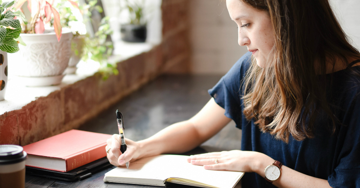 Young woman journaling at a window