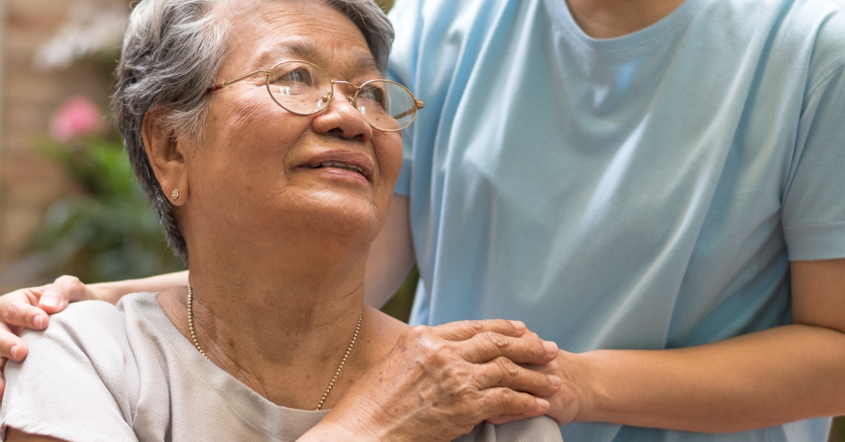 Elderly woman looking gratefully up at caregiver