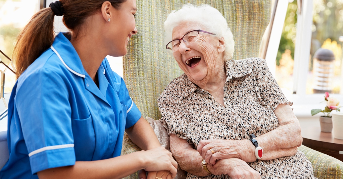 Elderly woman laughing with a caregiver