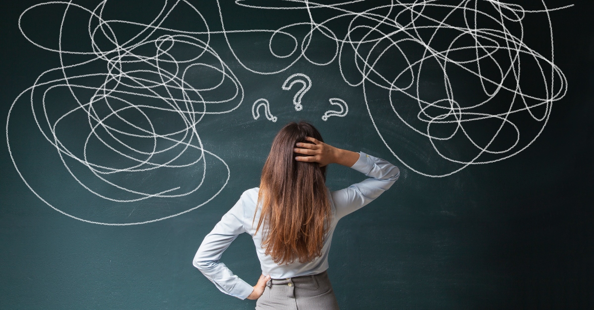 Confused woman looking at a jumble of lines on a chalkboard