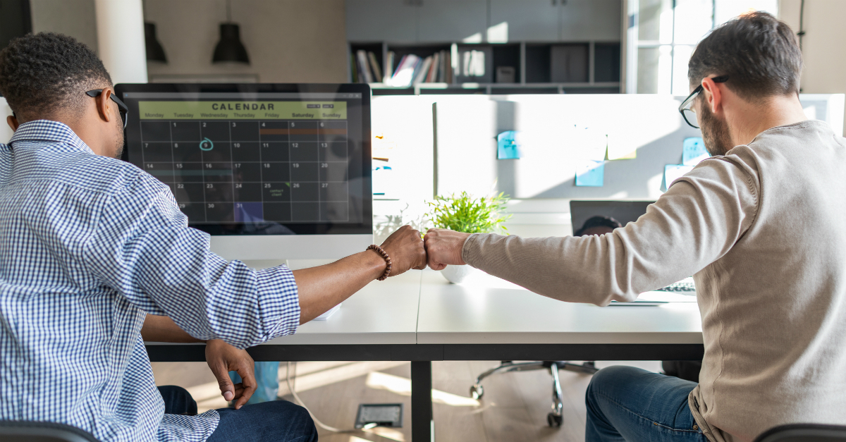 Coworkers giving a fist-bump at work