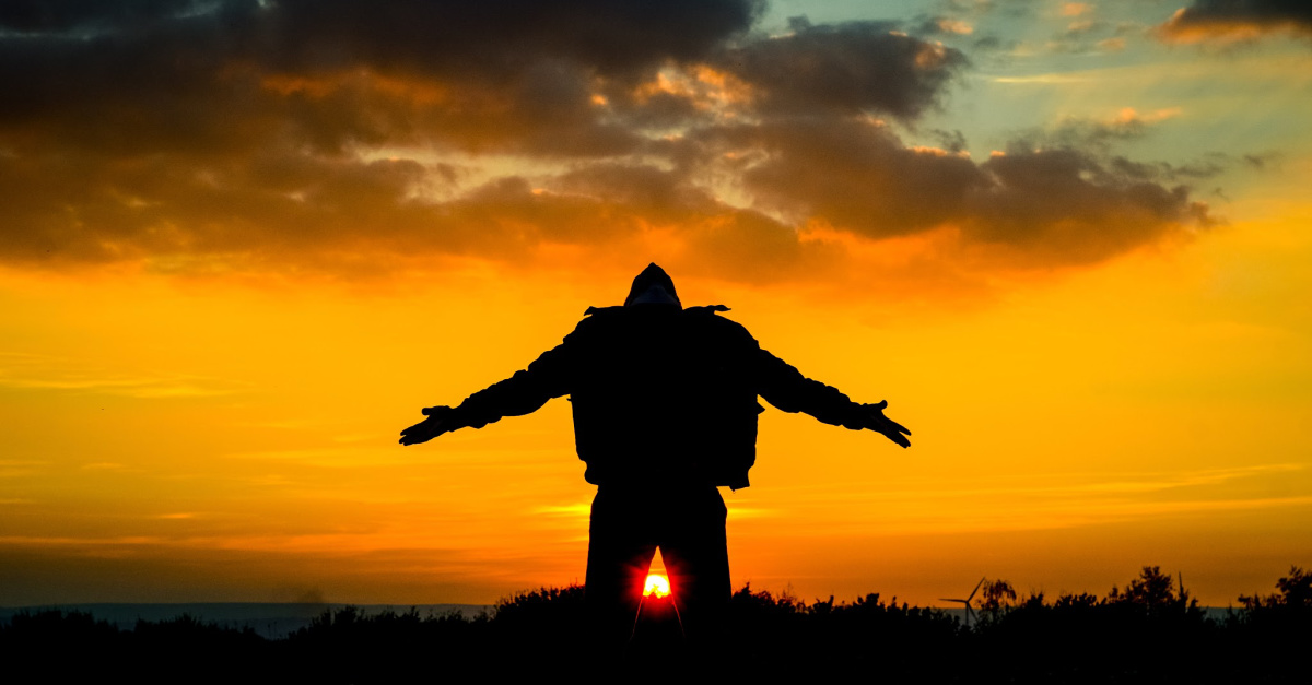 man on knees in worship at sunset outdoors