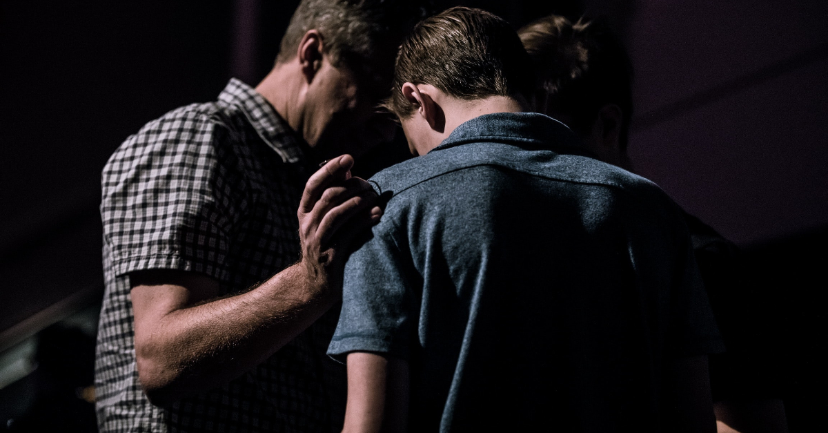 man intercessory praying for teen with hand on shoulder