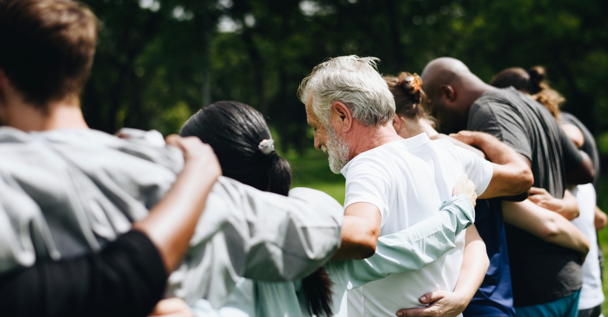 group of diverse adult friends group hug praying