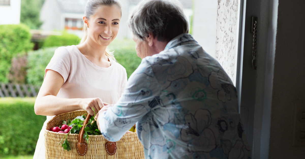 Woman bringing groceries to an elderly neighbor