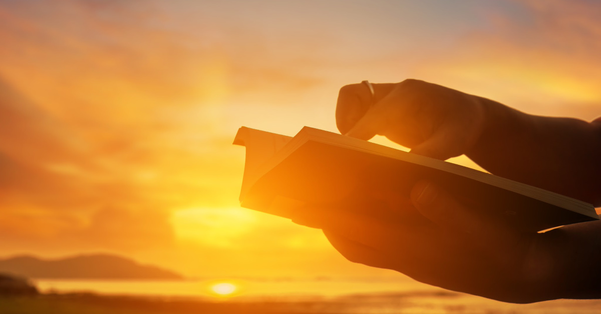 person holding Bible against sunset background, God provides