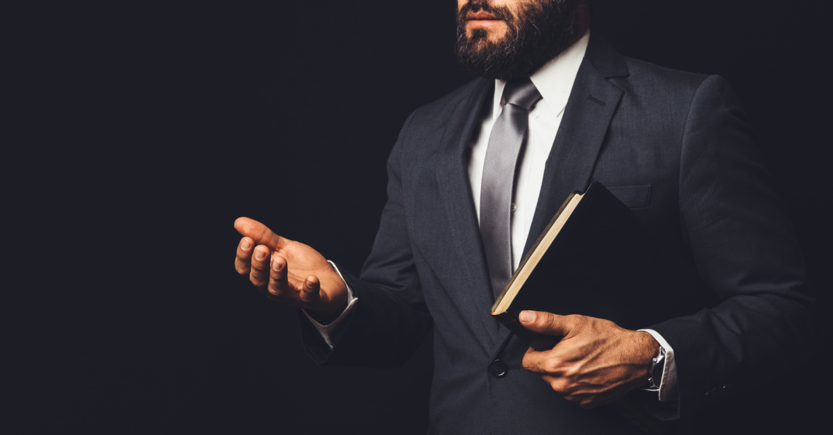 A man holding a bible and his hand out