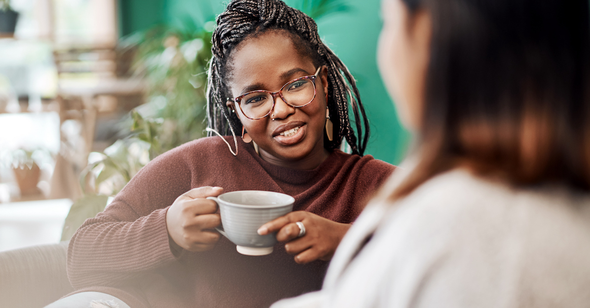 Female friends having coffee on sofa