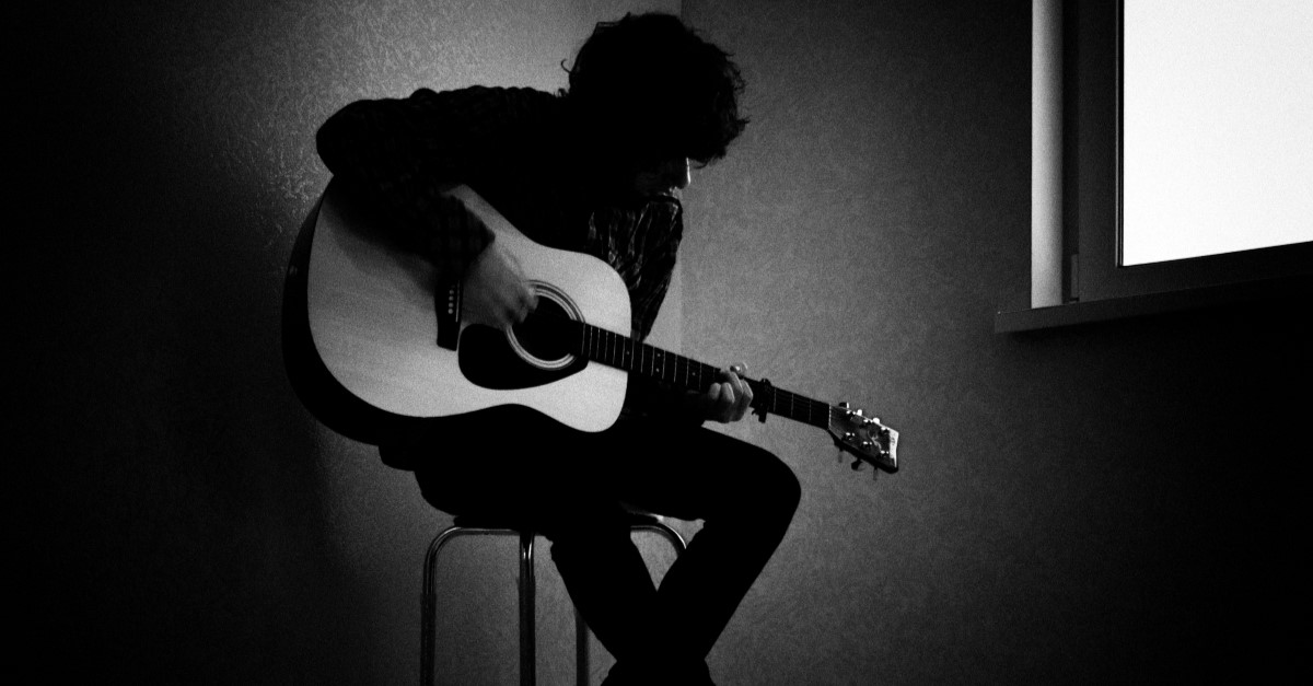 man playing guitar in dark room