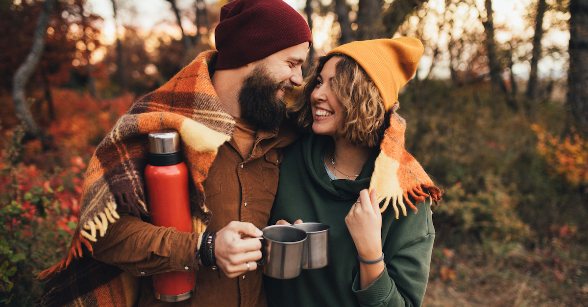 Cozy couple in fall with blankets and coffee hiking