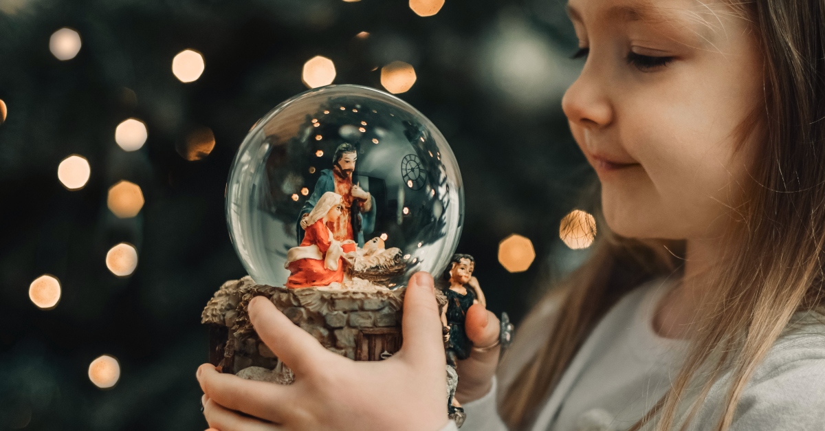 Little girl looking a nativity snow globe