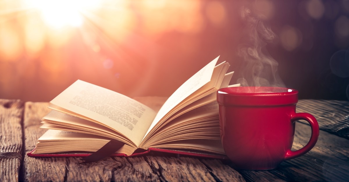 Sunny outdoors open book and coffee on wooden table, contemporary books by christians