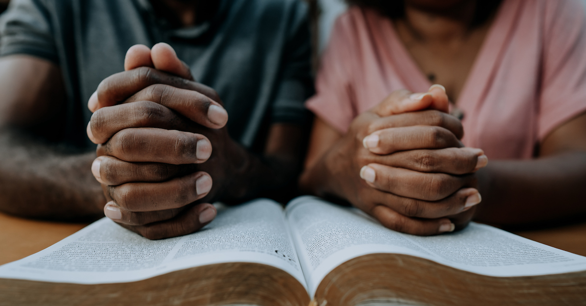 Couple reading Bible praying together