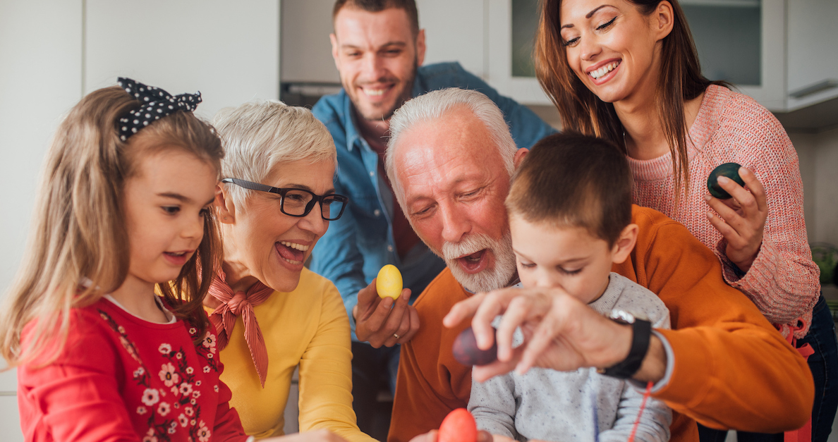 happy family with grandparents and grandchildren on easter painting eggs