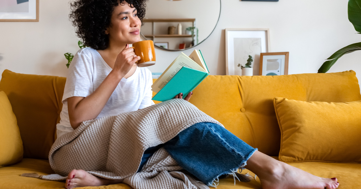 Woman joyfully enjoying her coffee on her couch.