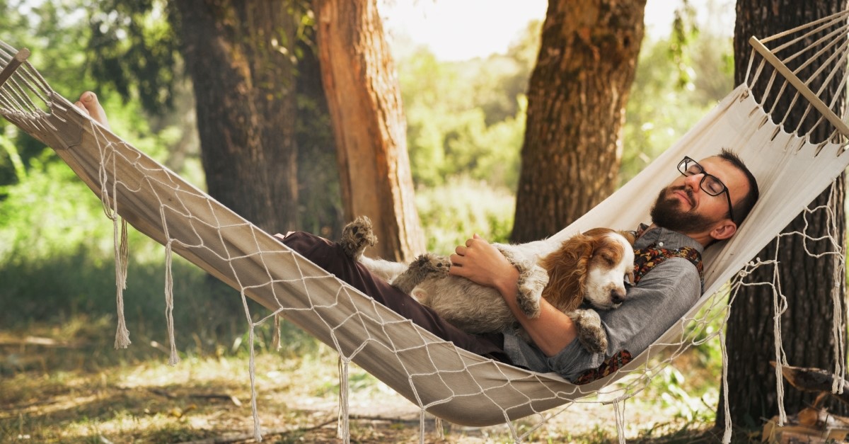 man resting in hammock with dog