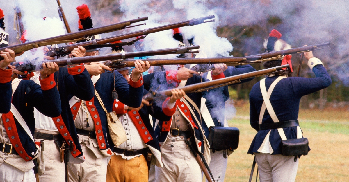 American Revolution battle reenactors firing rifles