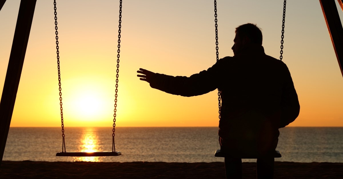 elderly man on swings reaching out to empty swing, dealing with grief