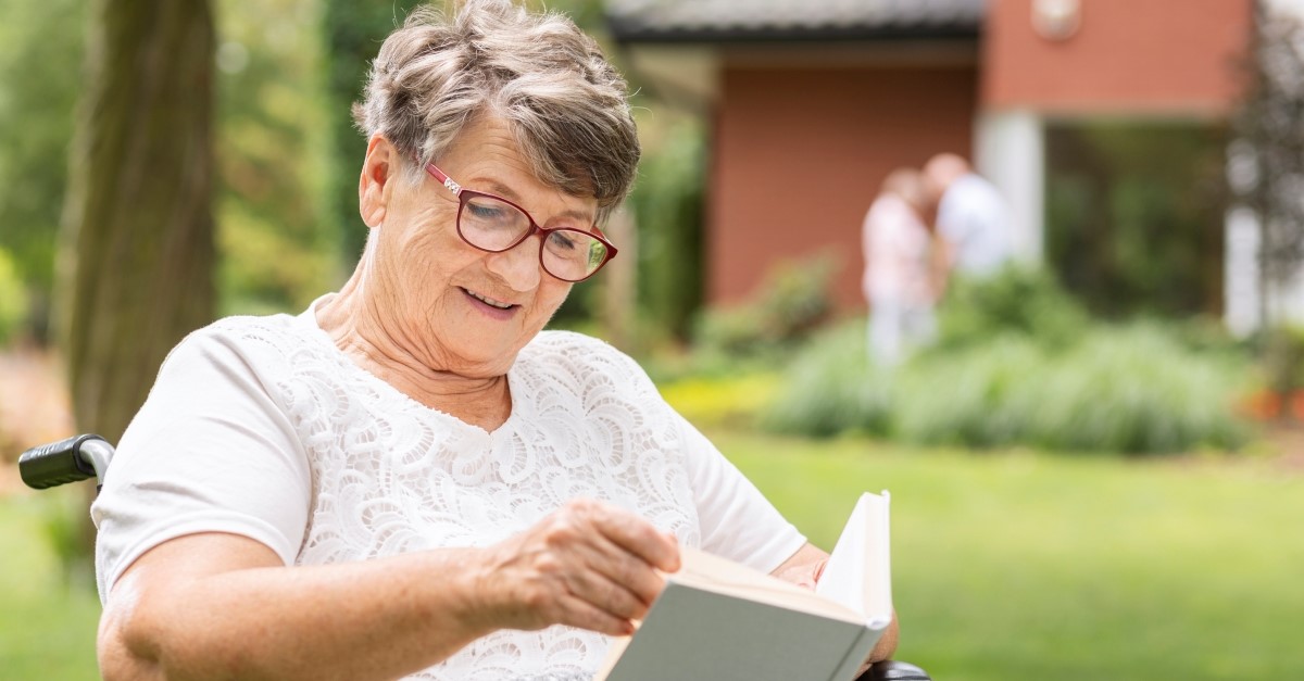 older woman reading book outside to illustrate seventh-day adventist makes you live longer