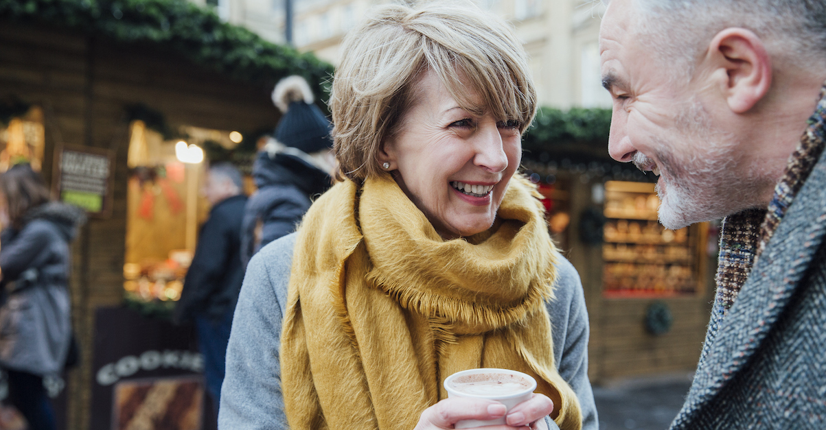 Happy senior couple on winter date in the cold drinking coffee