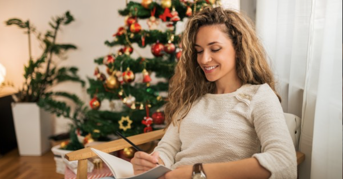 single woman alone journaling by Christmas tree