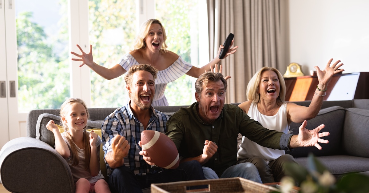 family watching football game excitedly together on sofa