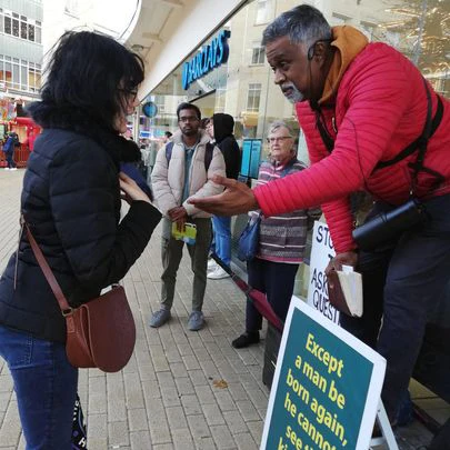 Street preacher Dia Moodley engages a young woman on a street in England