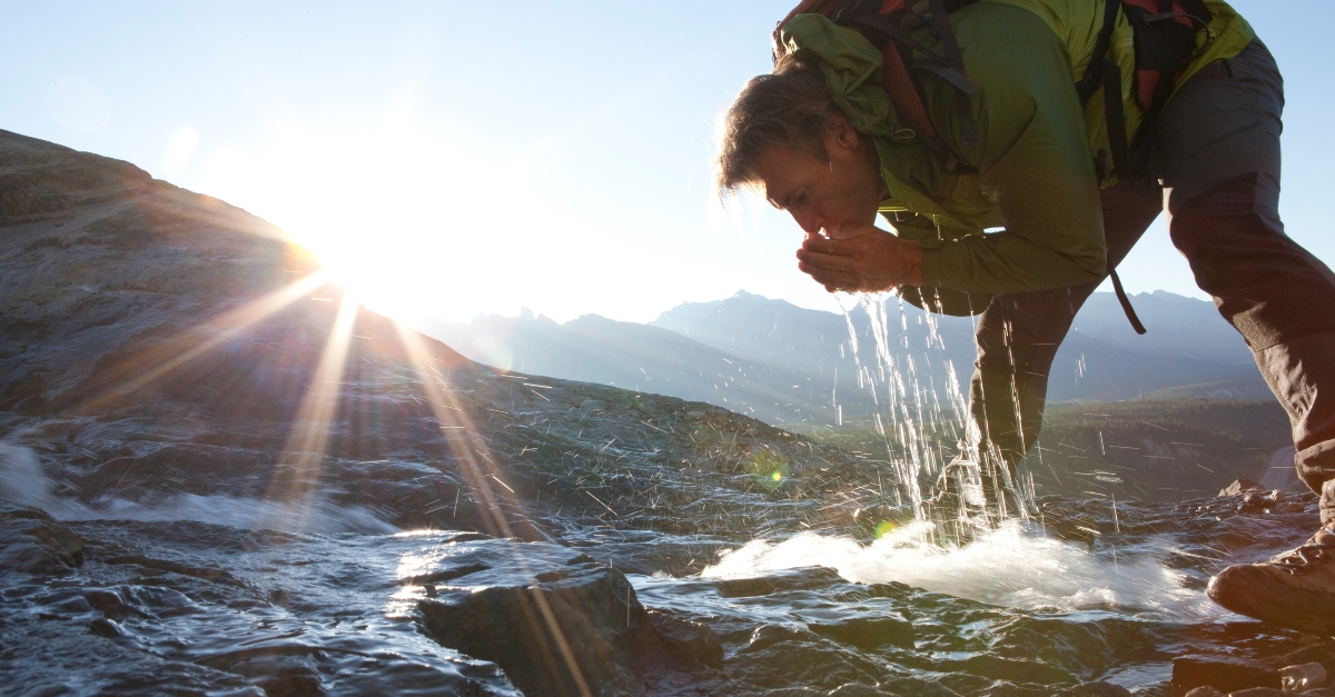 man drinking from a fresh spring in the mountains