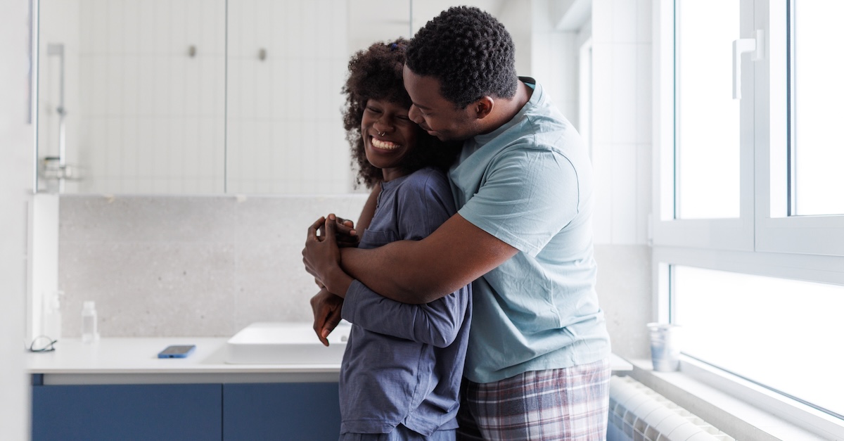 Happy cute married couple hugging in kitchen