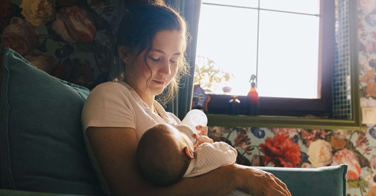 New mom postpartum feeding newborn baby in nursery