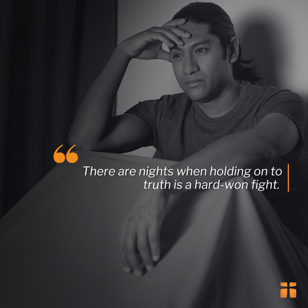 Man holding his hand to his head, sitting up in bed at night because he cant sleep. Article with 20 encouraging verses for when life is hard.